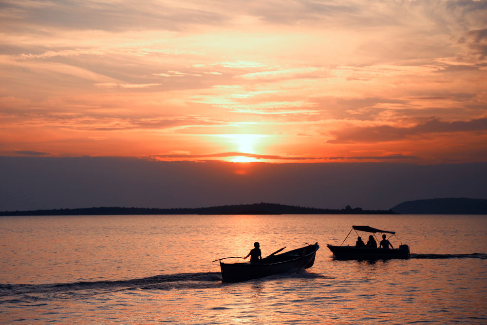 two boats pass each other under an orange sky