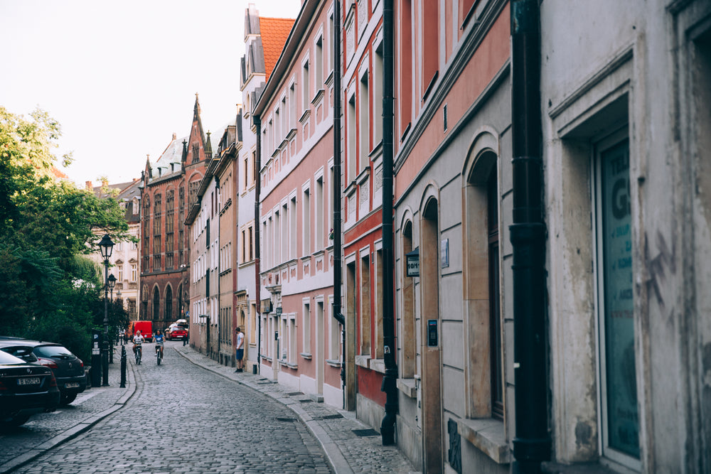 two cyclists roll down a picturesque cobbled street