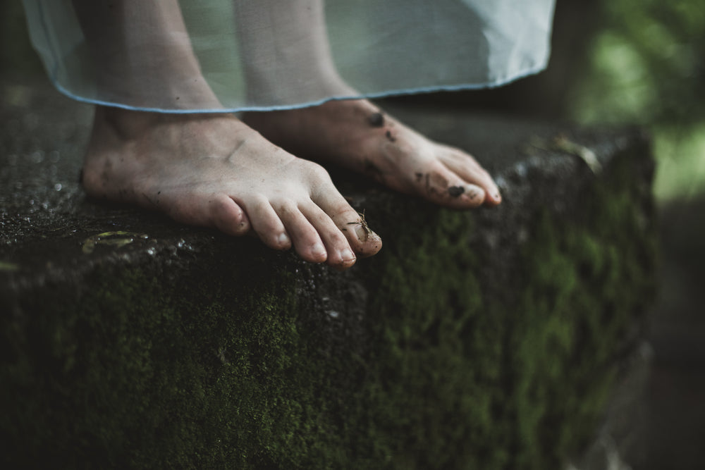 two dirty feet on mossy ground