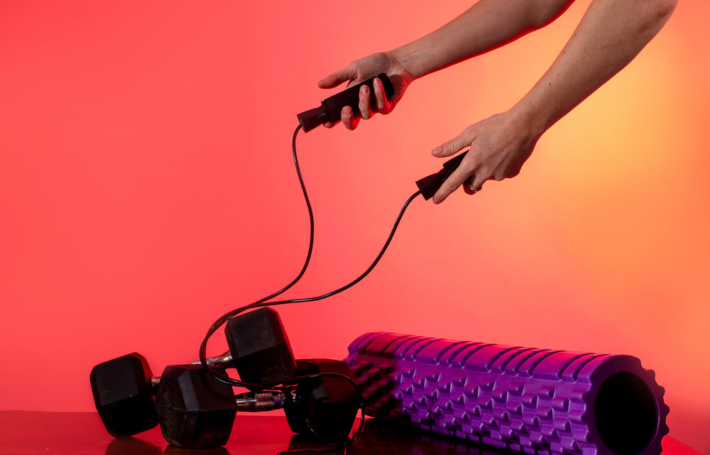 two dumbells and a foam roller on a wooden table