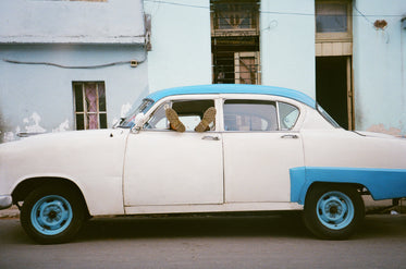 two feet stick out the front window of a white car