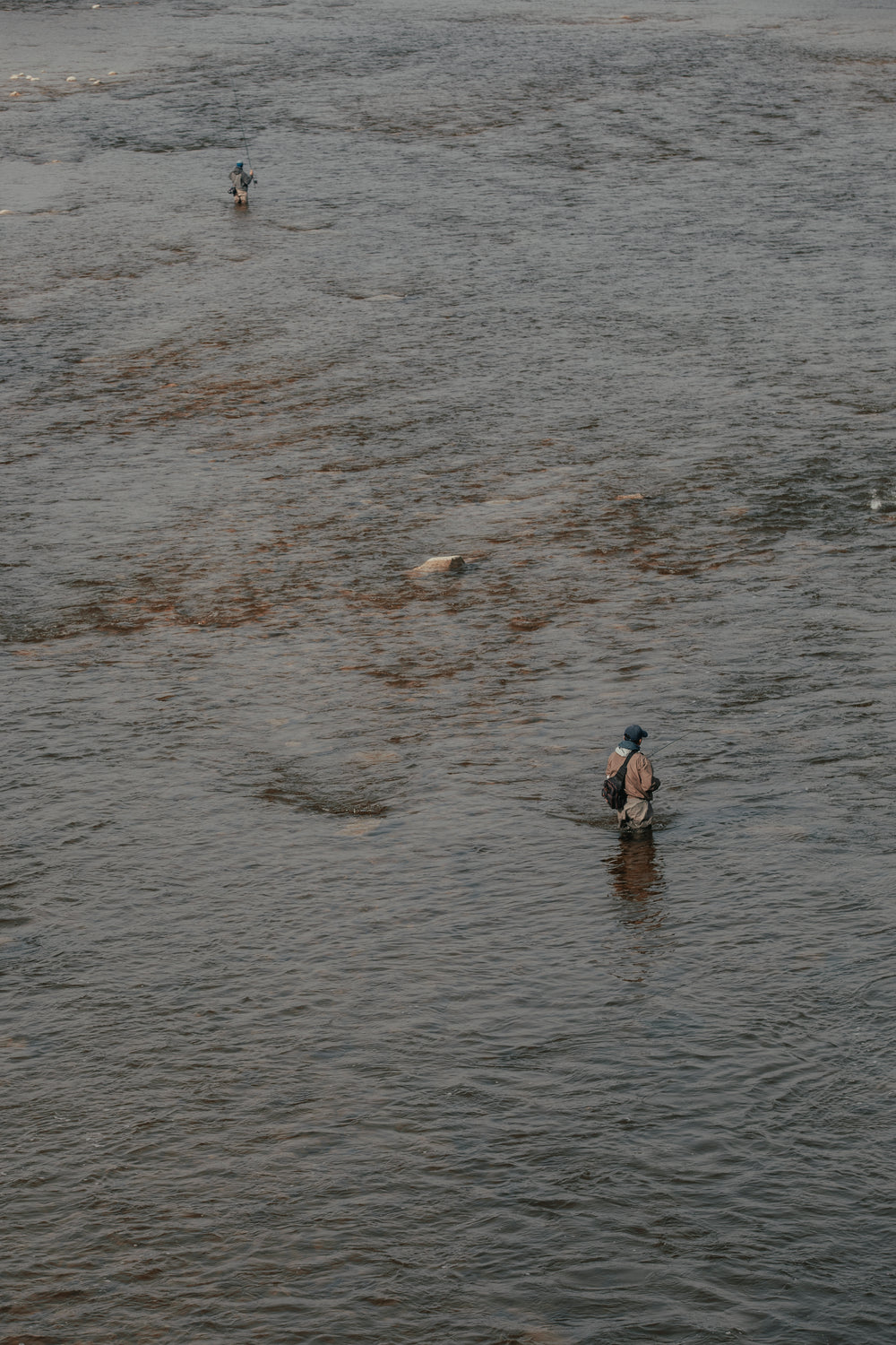 two fishermen stand in river