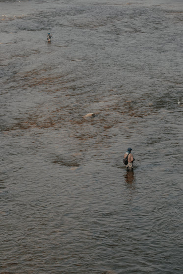 two fishermen stand in river