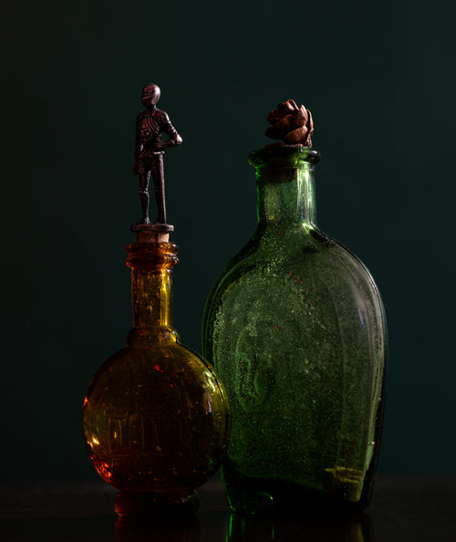 two glass bottles with ornate tops