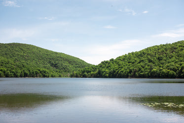 two green hills by a lake