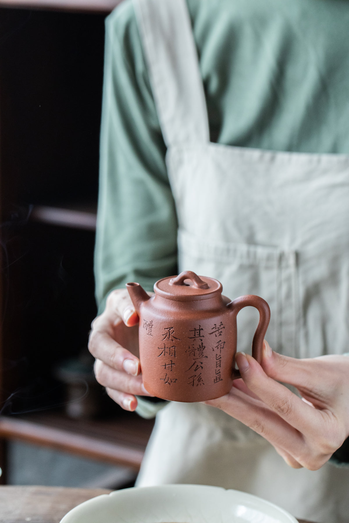 two hands holding chinese teapot
