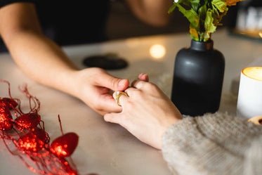 two hands reach to hold each other across the table