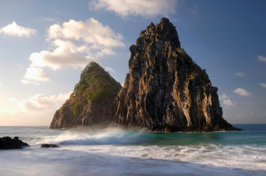 two large mountains rocks sit in a wavy ocean