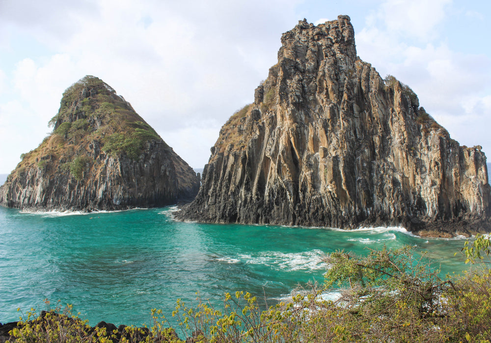 two large rock formations sit in aqua blue water