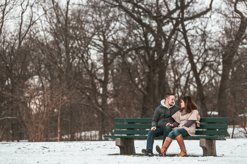 two lovers smile on a bench in the woods