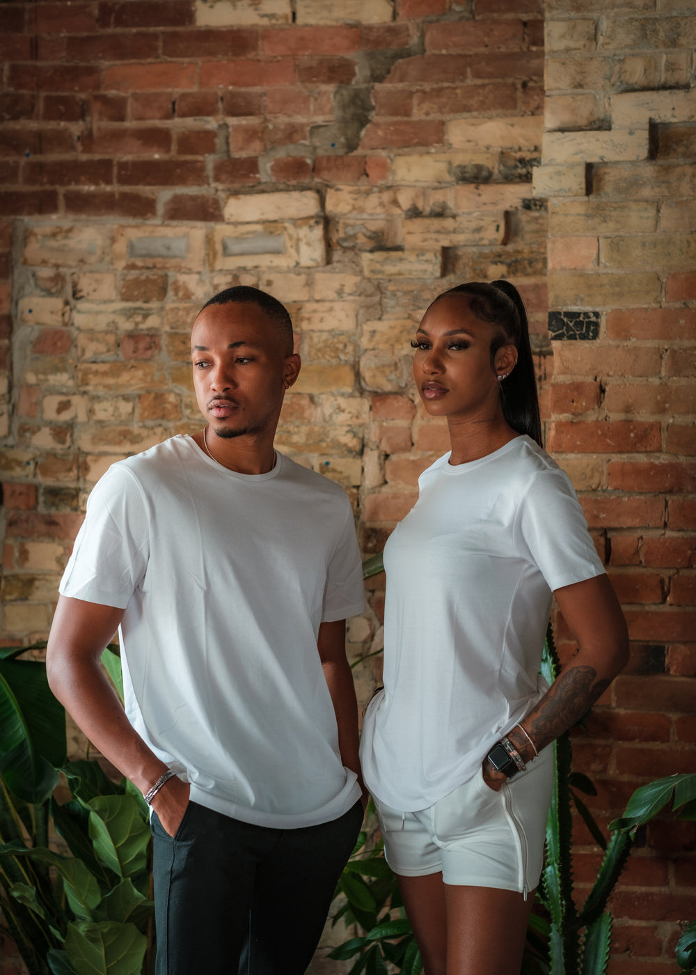 Two Models In White Stand In Front Of Red Brick