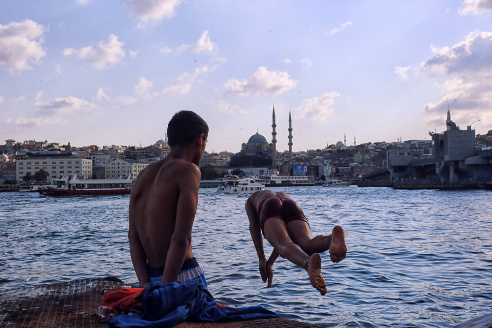 two people by blue water with one captured diving in