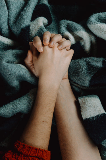 two people holds hands against a blue blanket