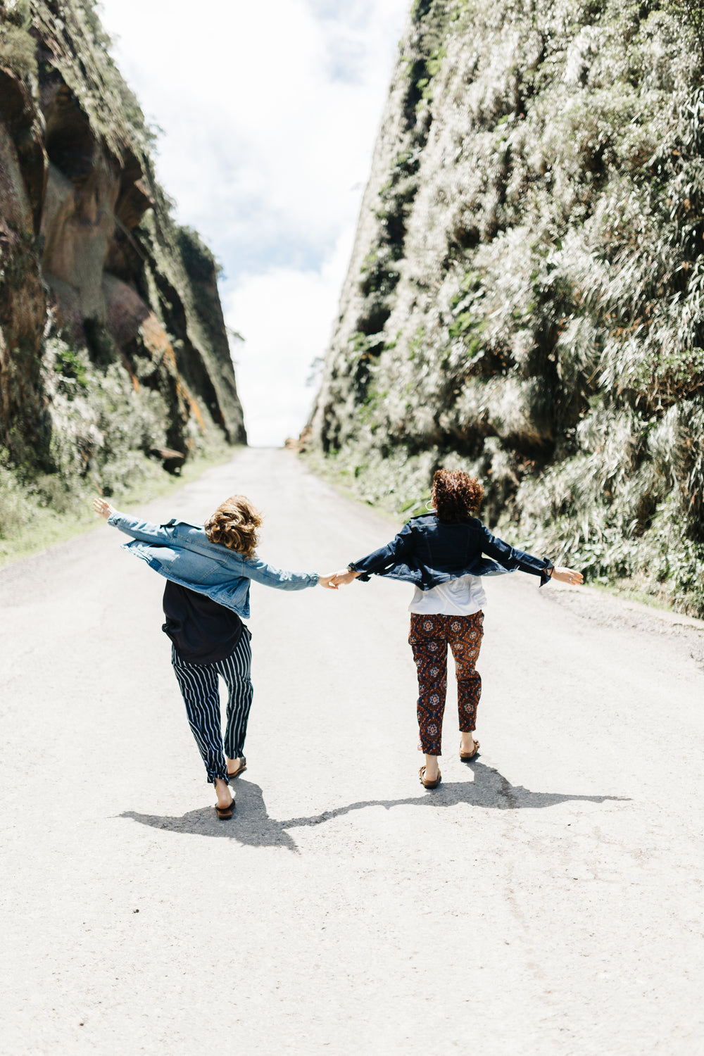 two people holds hands as they walk up a road