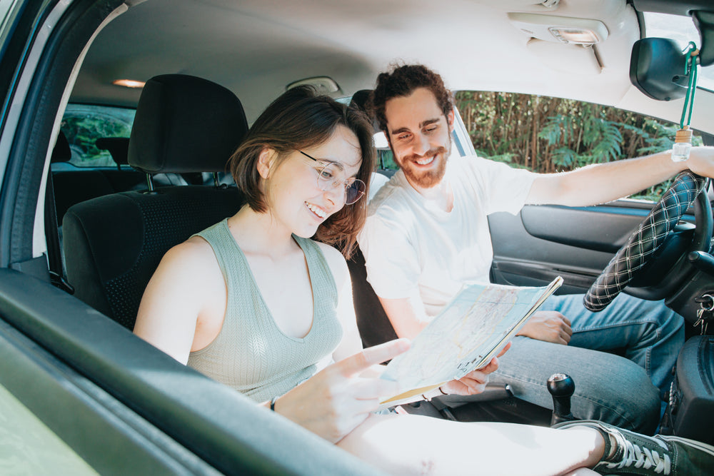  two people in a car look at a map while smiling