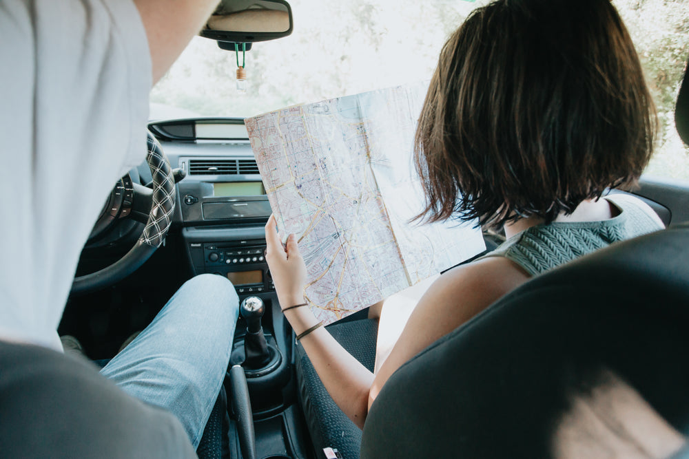 two people in a car with a large map held up