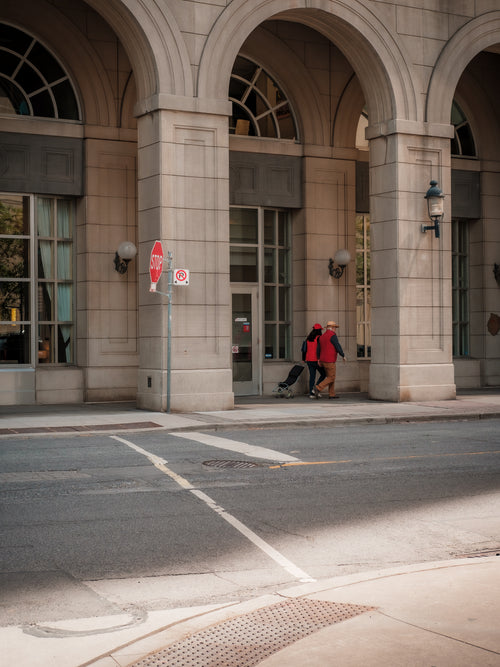 two people in red walk under a city building archway