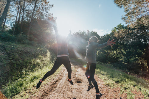 two people jump in celebration on a hiking trail