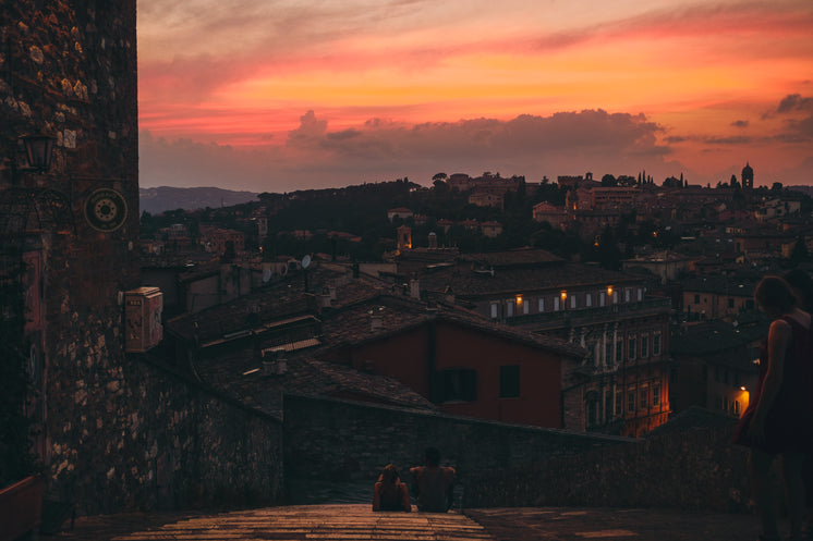 Two People On A Roof Together Taking In The Sunset