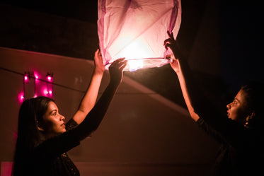 two people raising a lantern