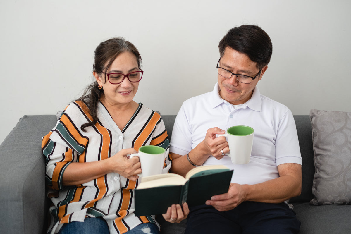 two people read a book sitting on a couch