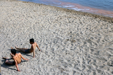 two people relax laying down on a sandy beach