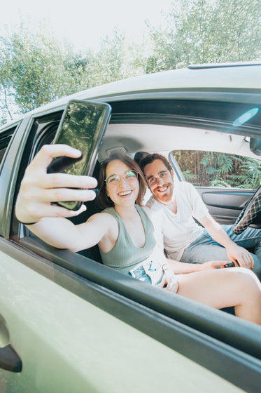 two people sat in a car take a selfie together