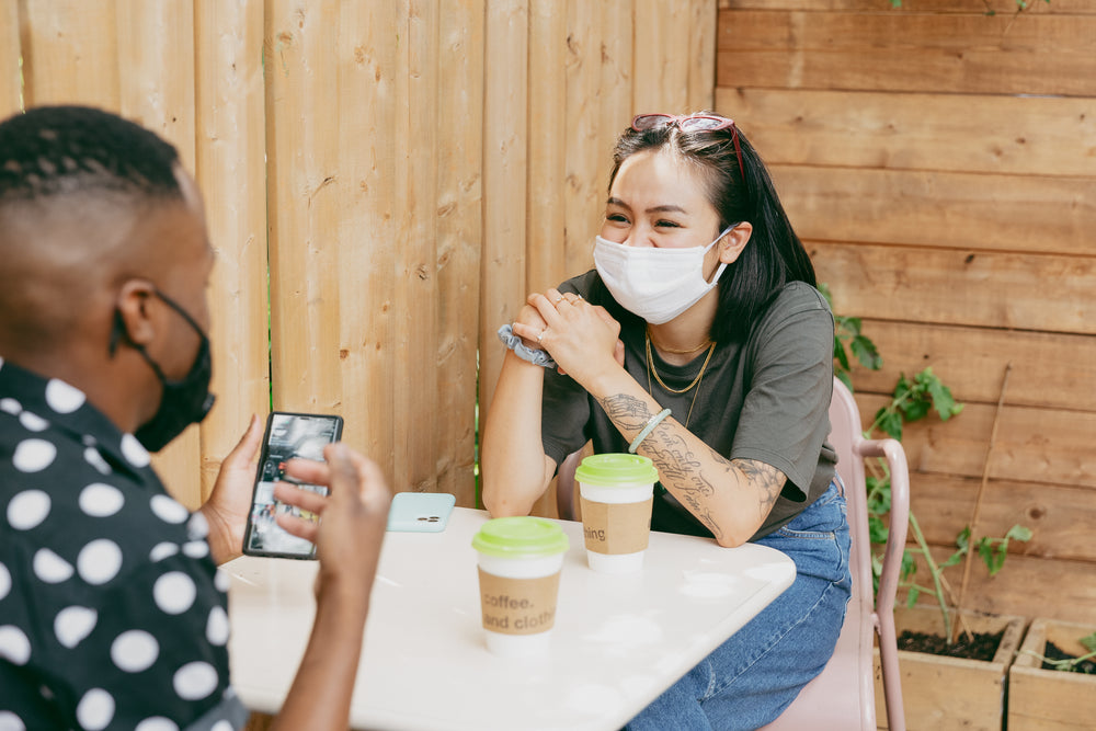 two people share a coffee while socially distancing