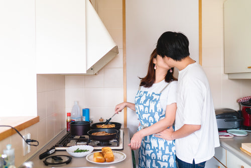 two people share a kiss in the kitchen cooking