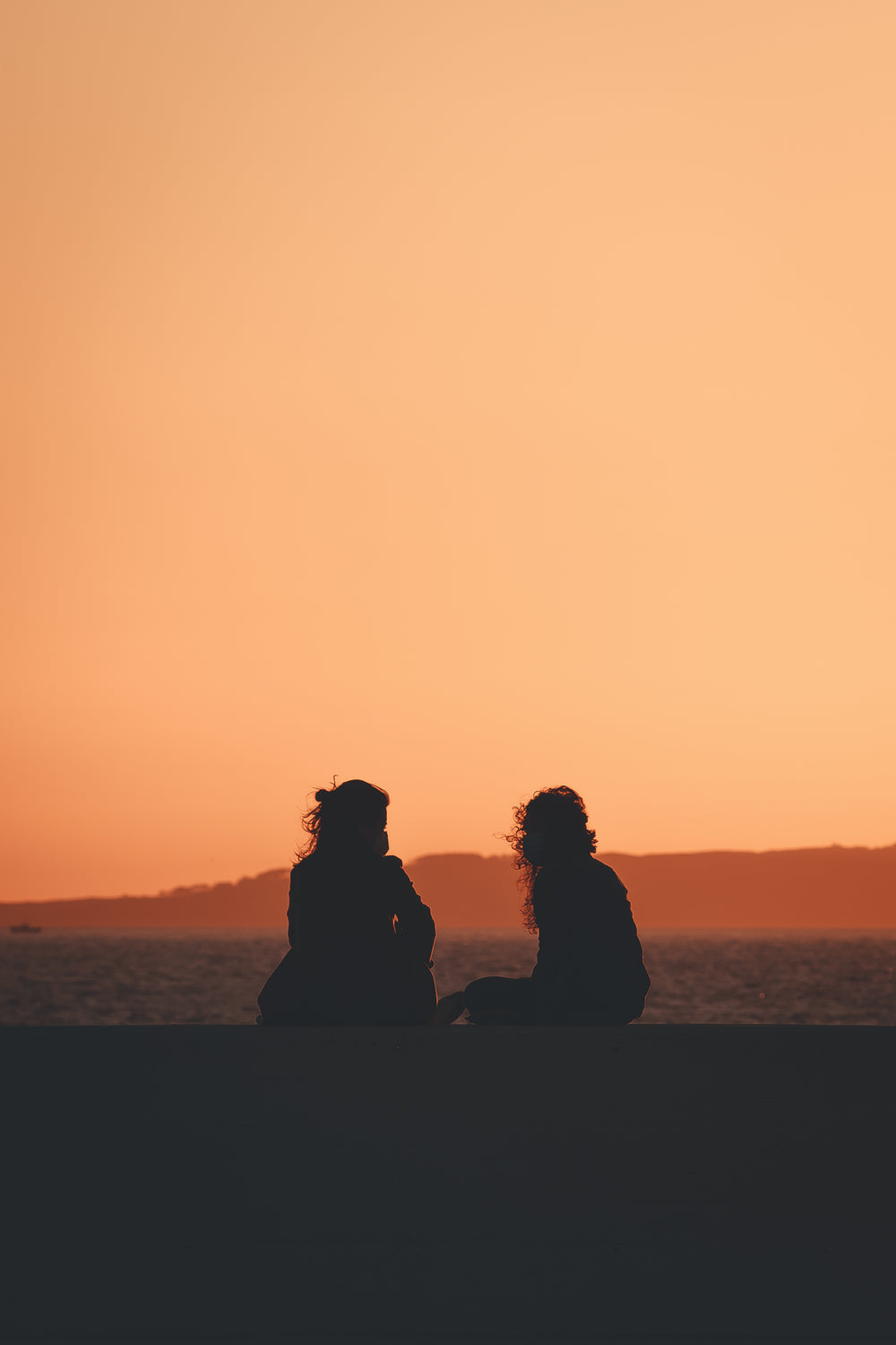 two people silhouetted by the settings sun