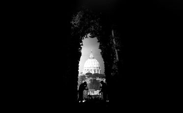 two people silhouetted working in an archway of trees