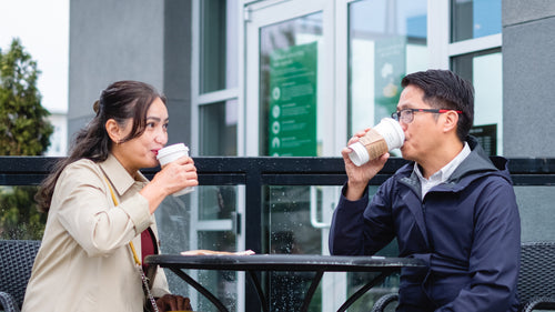 two people sip from takeout cups on a patio