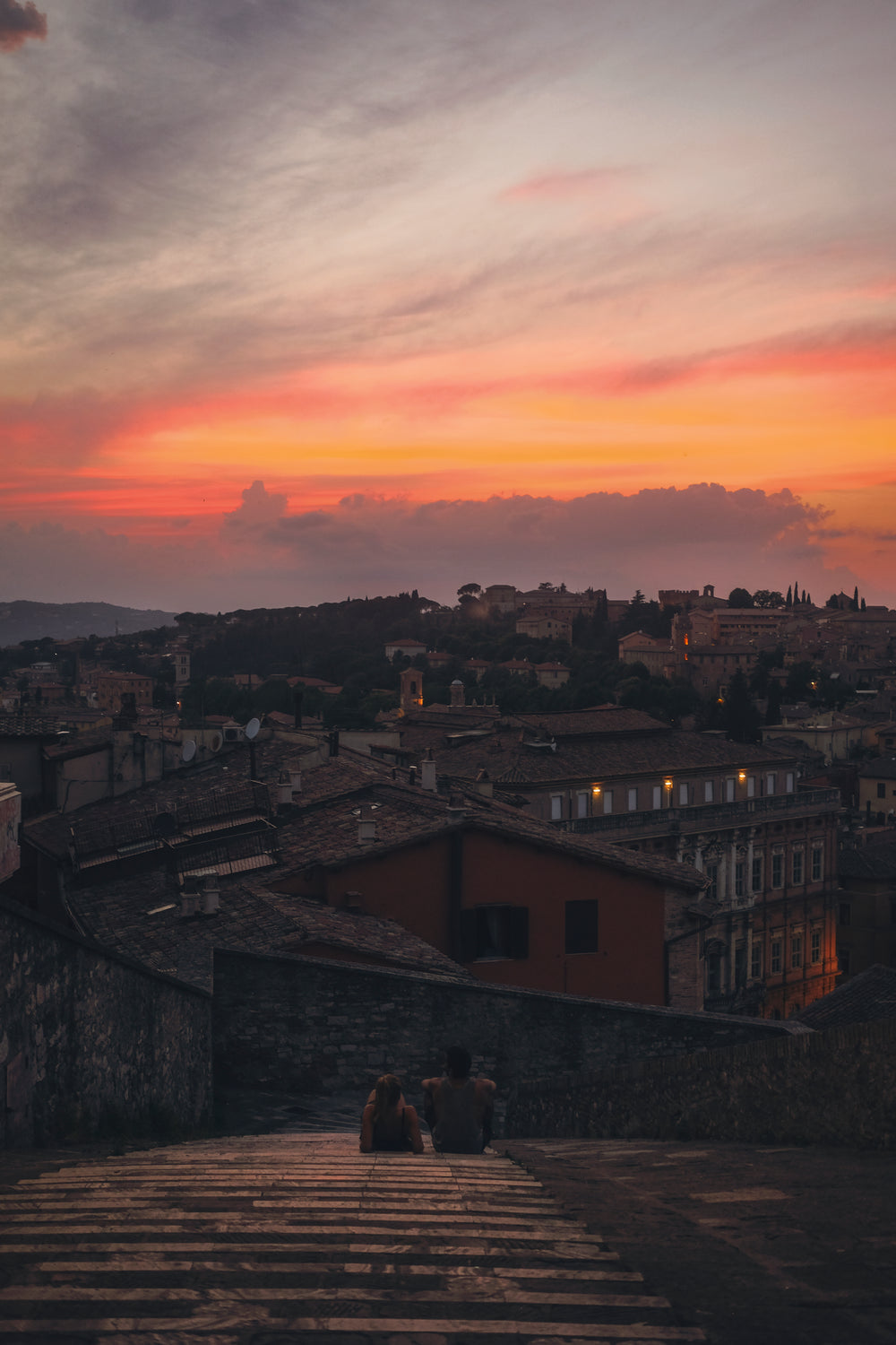 two people sit high up to take in the evening sunset