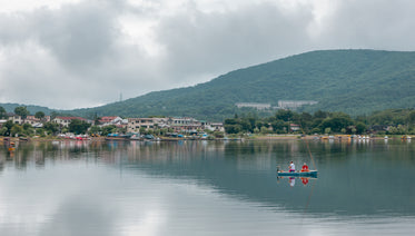 two people sit in a boat on still waters