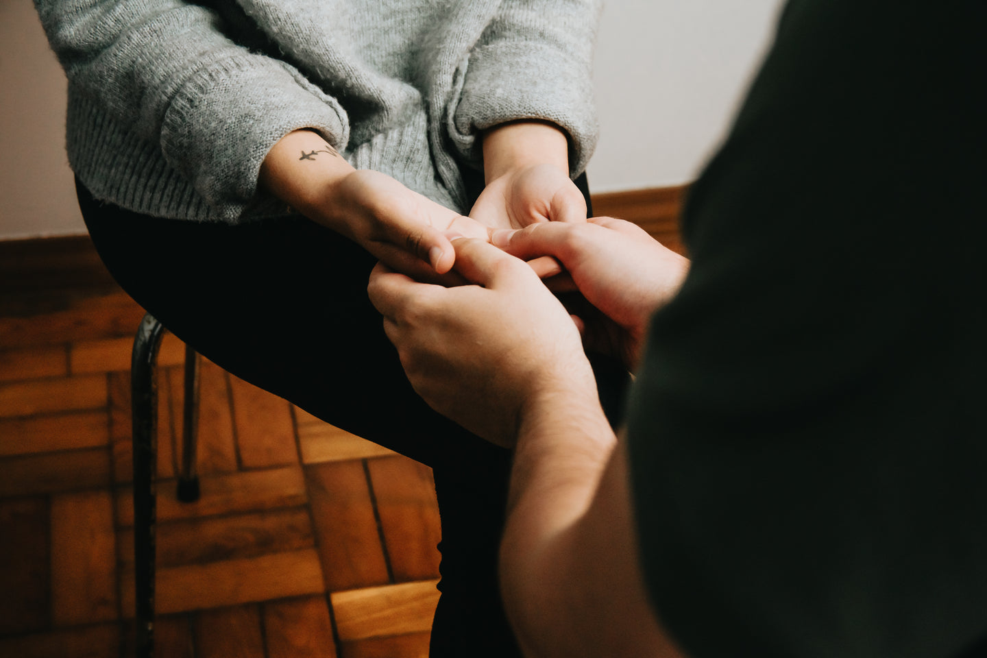 Two People Sitting Across From Each Other And Holding Hands