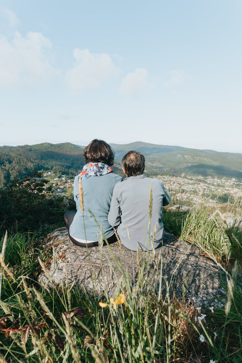 two people sitting on rock facing away from camera