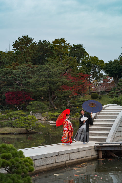 two people smile holding umbrellas on a walkway