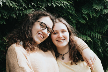 two people smile standing in front of a cedar tree