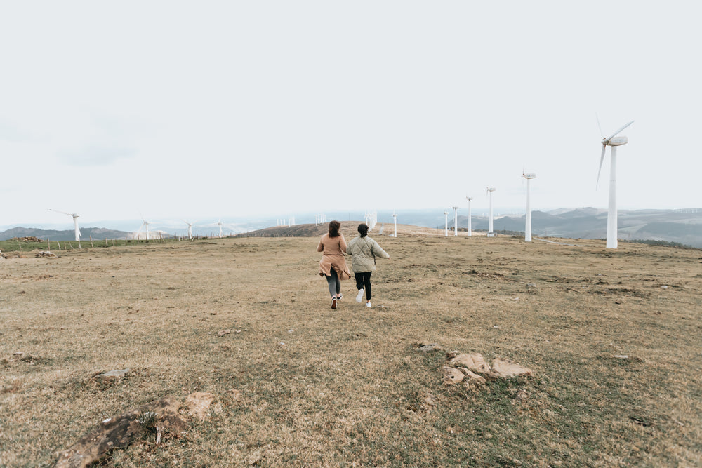 two people walk among tall white windmills