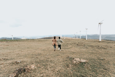two people walk among tall white windmills