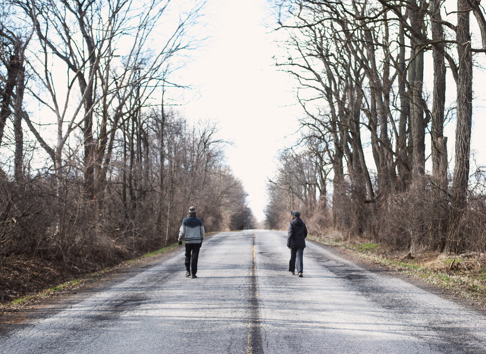 two people walking on empty road