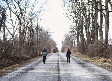 two people walking on empty road