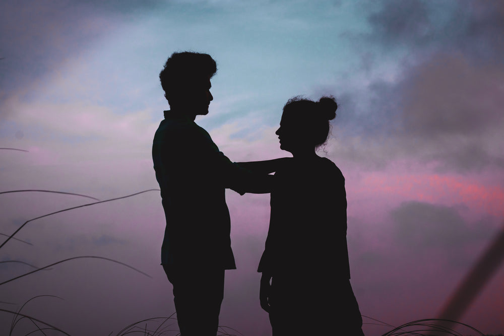 two silhouetted people stand facing each other