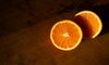 two slices of orange lay on a sunlit cutting board
