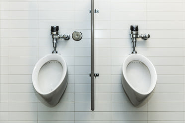 two urinals on white tile wall