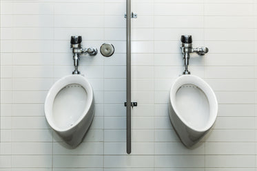 two urinals on white tile wall