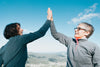 two woman high fiving under blue sky