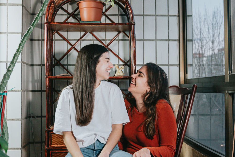 two woman smile wide as they look at each other