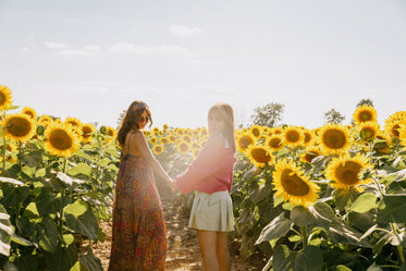 two woman standing in a sunflower field together