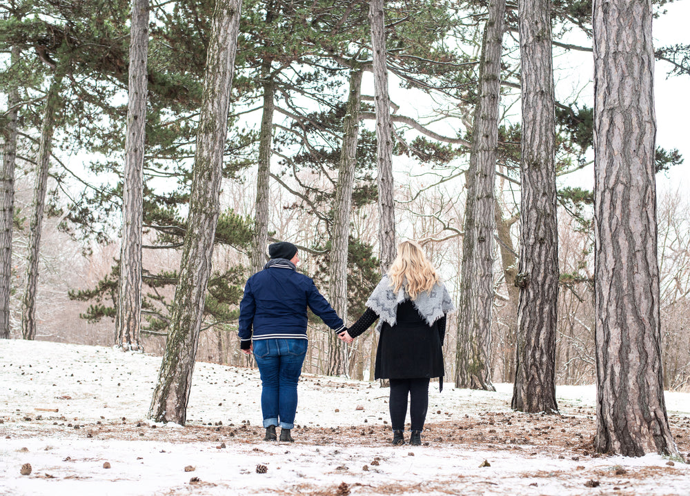 two women hold hands in the snowy woods